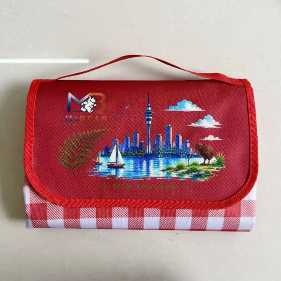 MC Bear NZ Picnic Mat folded into its red carry bag with the New Zealand print