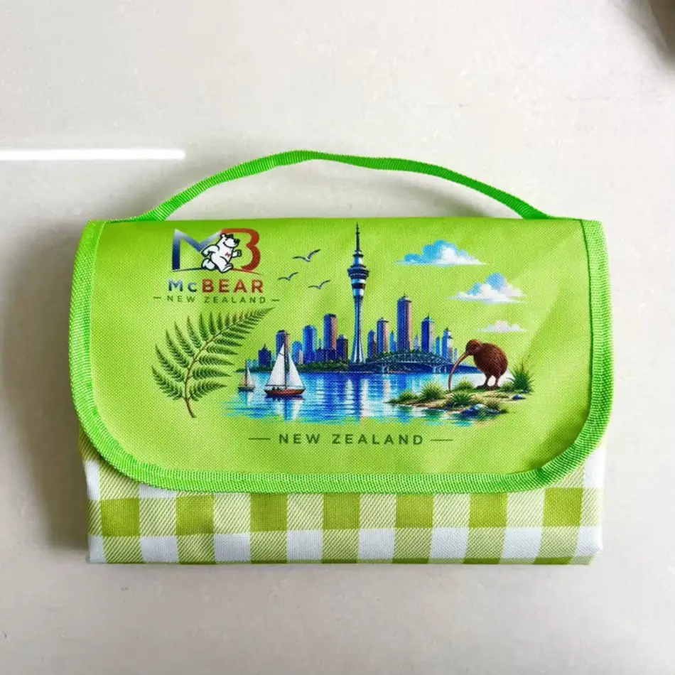 MC Bear NZ Picnic Mat folded into its green carry bag with the New Zealand print